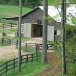 Just below the house sits a pretty, gray/blue barn at this equestrian estate